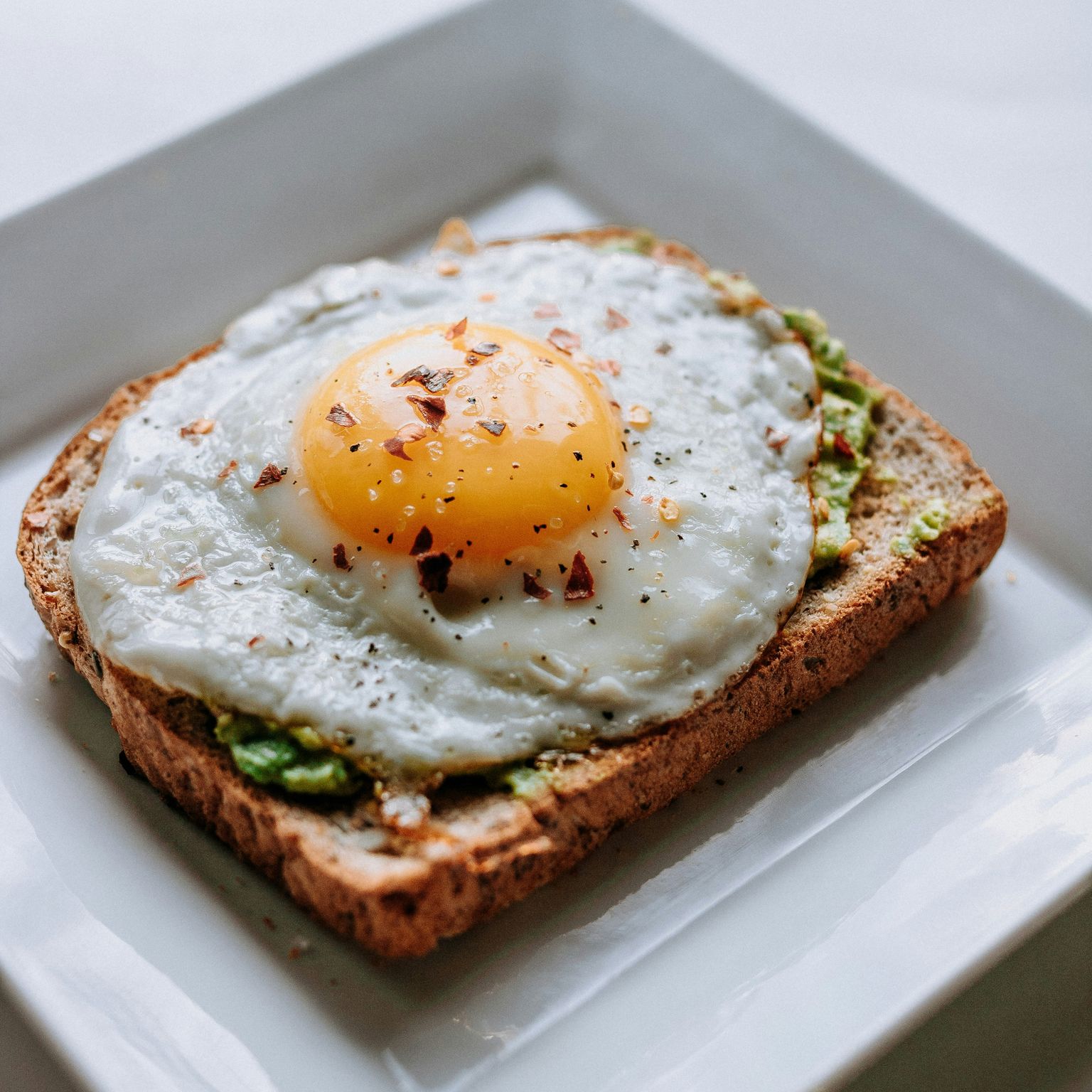 Avokádový toast so volským okom na bielom tanieri